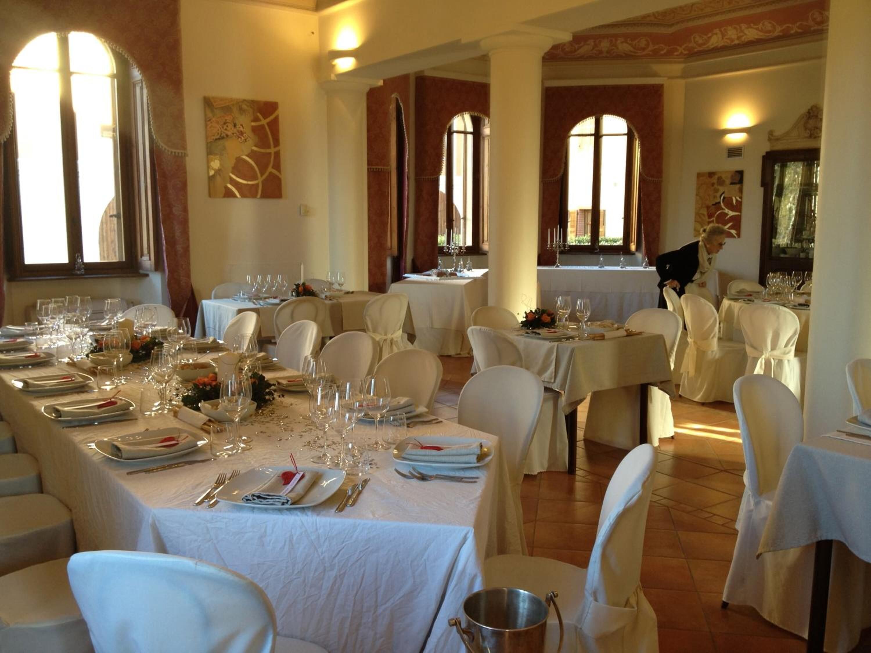 A banquet hall with multiple tables set for dining, each with white tablecloths and chairs.