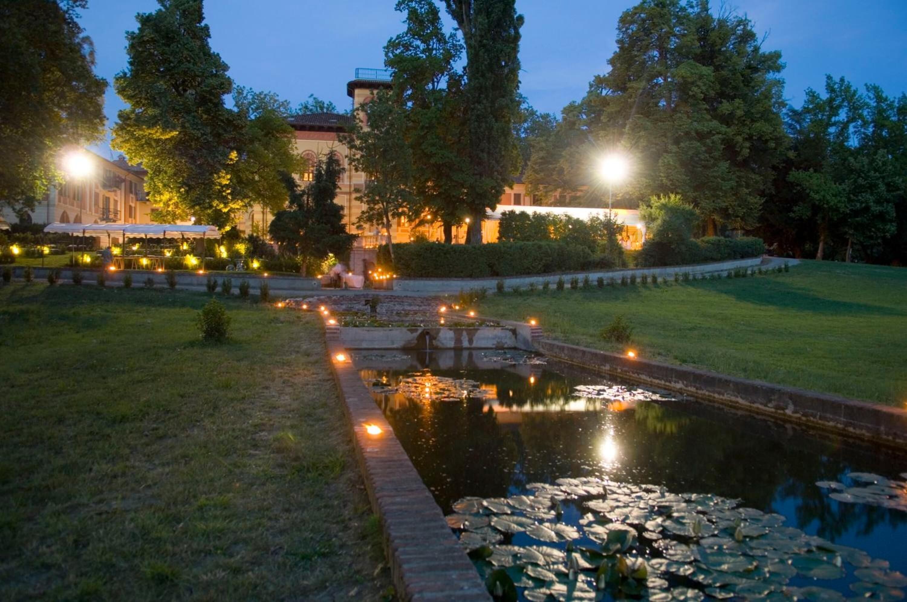 A serene garden with a pond, pathways, and a building in the background.