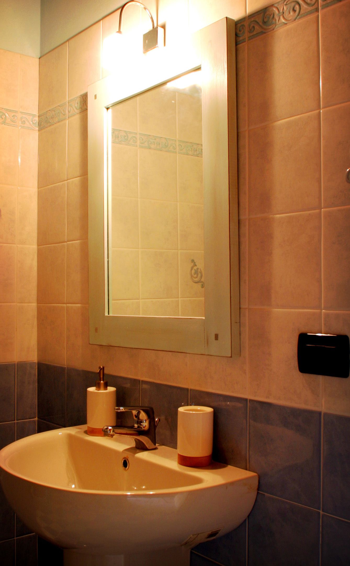 A bathroom with a sink, mirror, and towel dispenser.