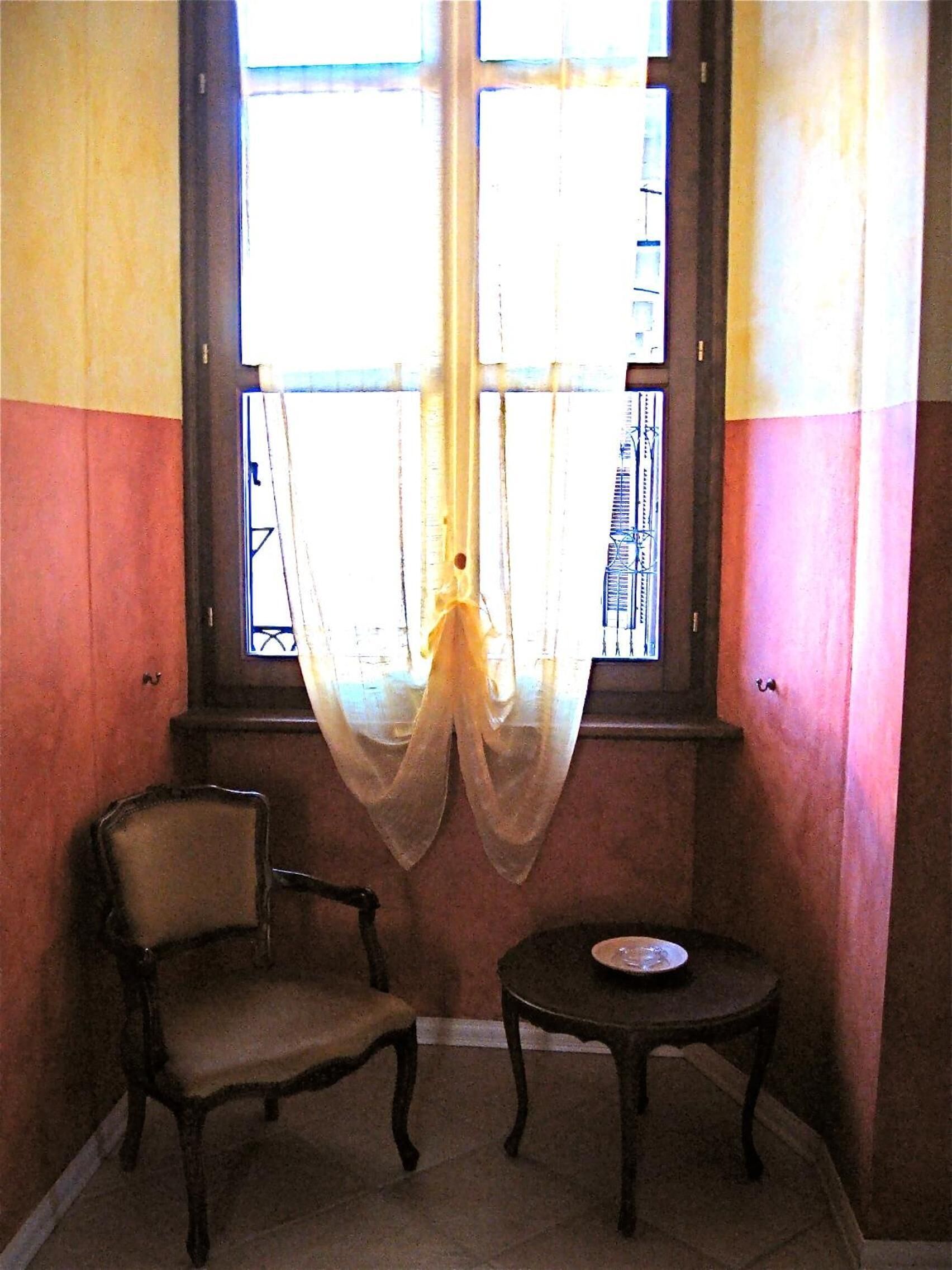 A room with a window, a chair, and a small table.