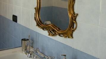 A bathroom with a large ornate gold-framed mirror, a sink with a modern faucet, and blue and white tiled walls.