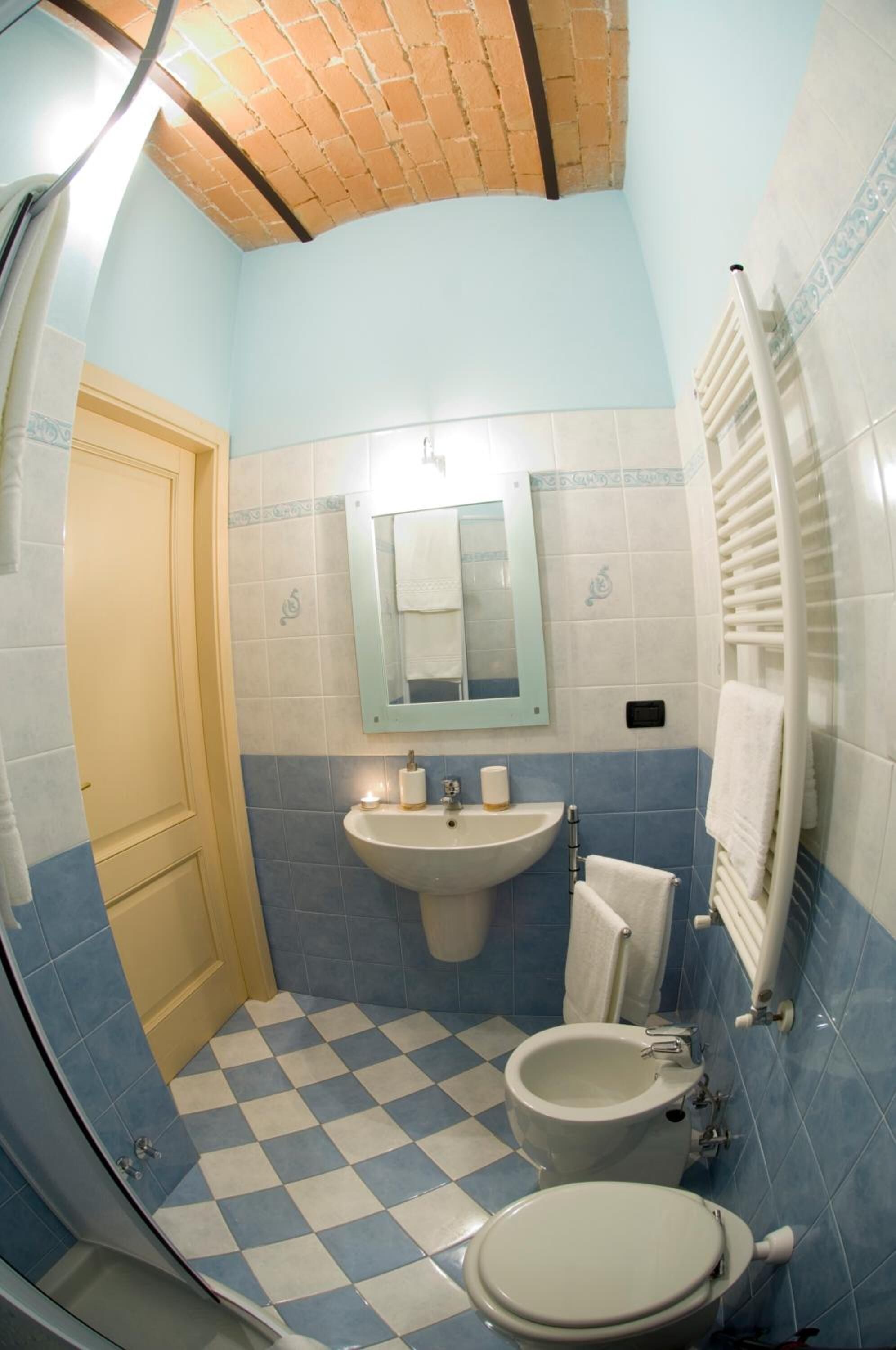 A bathroom with a checkered floor, a sink, a toilet, and a mirror.