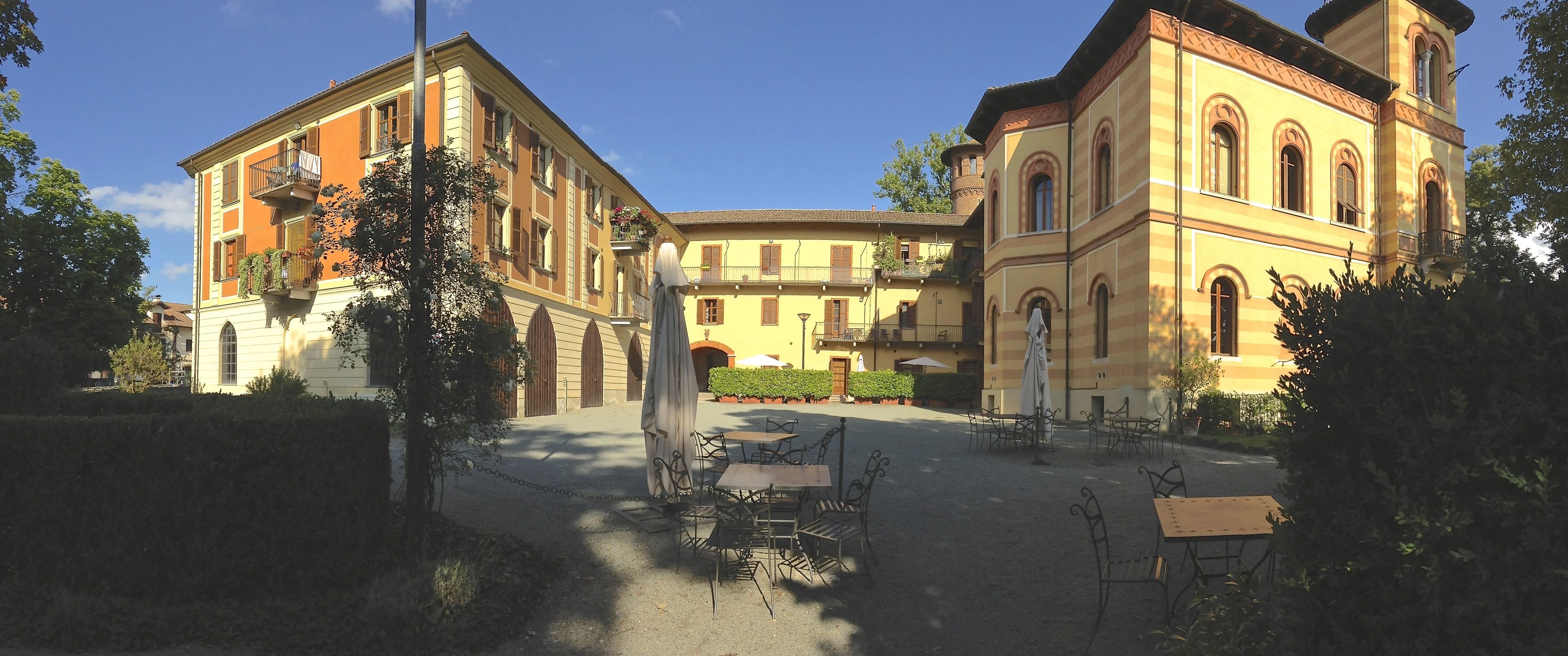 A courtyard with outdoor seating, surrounded by historic buildings with balconies and arched windows.