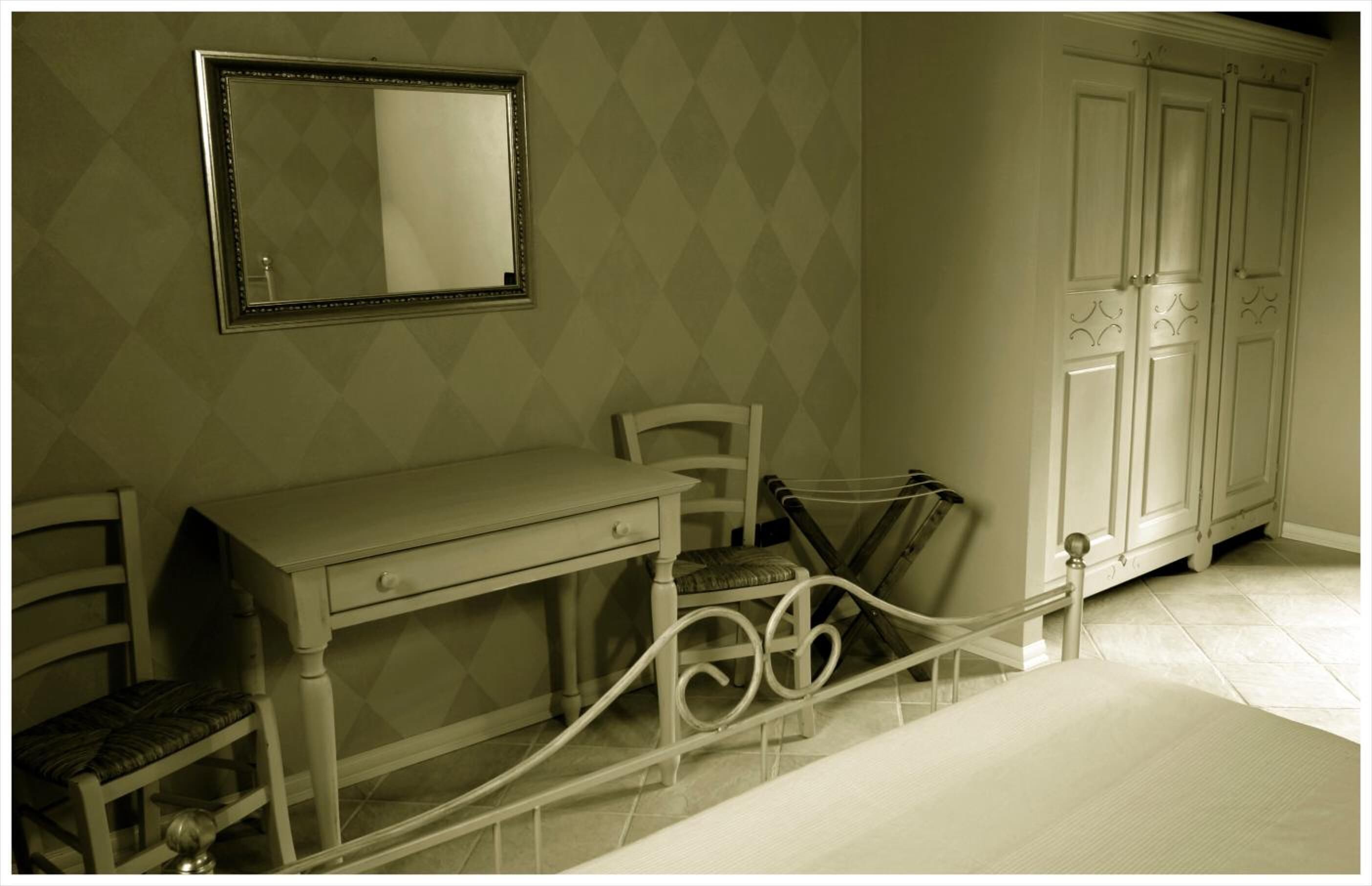 A bedroom with a bed, a desk, a chair, a wardrobe, and a mirror.