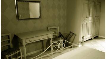 A bedroom with a bed, a desk, a chair, a wardrobe, and a mirror.