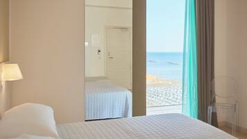 Habitació d'hotel amb llit, una cadira i vista a la platja.