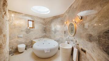 A bathroom with a freestanding bathtub, a round mirror, and a wall-mounted vanity.
