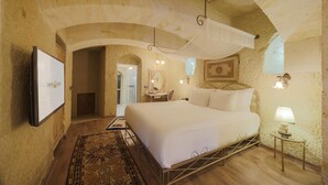 Un dormitorio con una cama grande, televisión, escritorio y lámpara.