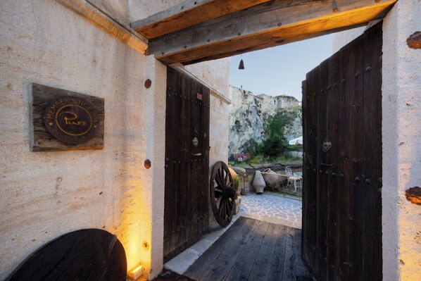 A rustic entrance with wooden doors and a stone pathway leading to a courtyard.