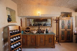 A wine cellar with wooden cabinets, a wine rack, and a mirror above a sink. - Tafoni Houses Cave Hotel (Ürgüp)