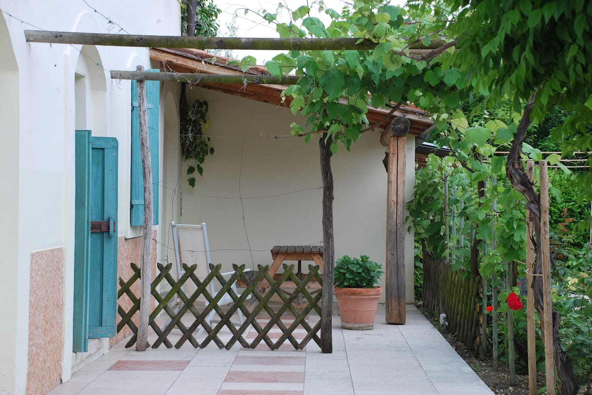 A covered outdoor area with a wooden lattice fence, a potted plant, and a small table.