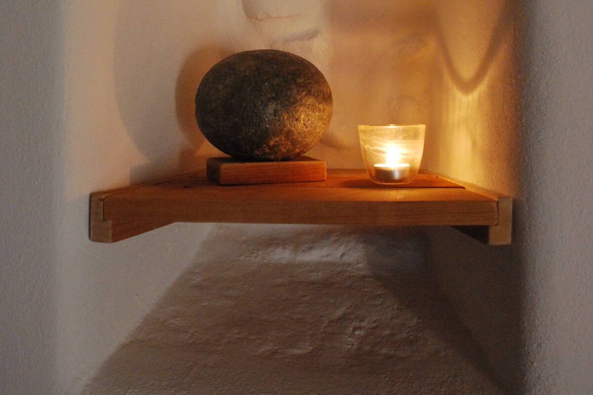 A shelf with a stone, a candle, and a wooden block.