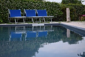 A swimming pool with three blue lounge chairs and a stone pillar. - La Tinassara (Lazise)