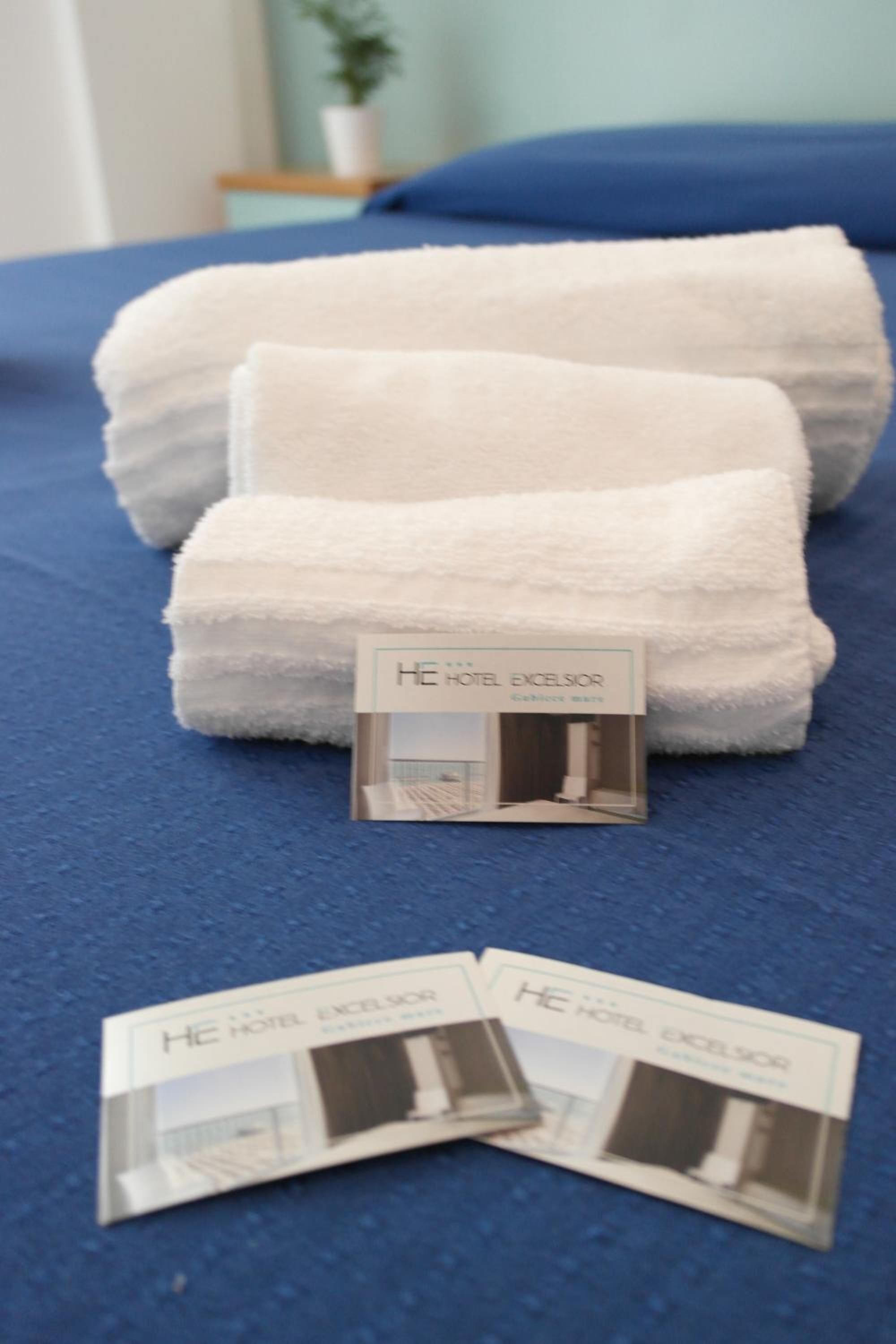 A bed with white towels and a hotel brochure on a blue bedspread.