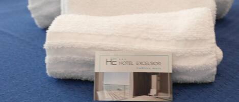 A bed with white towels and a hotel brochure on a blue bedspread.