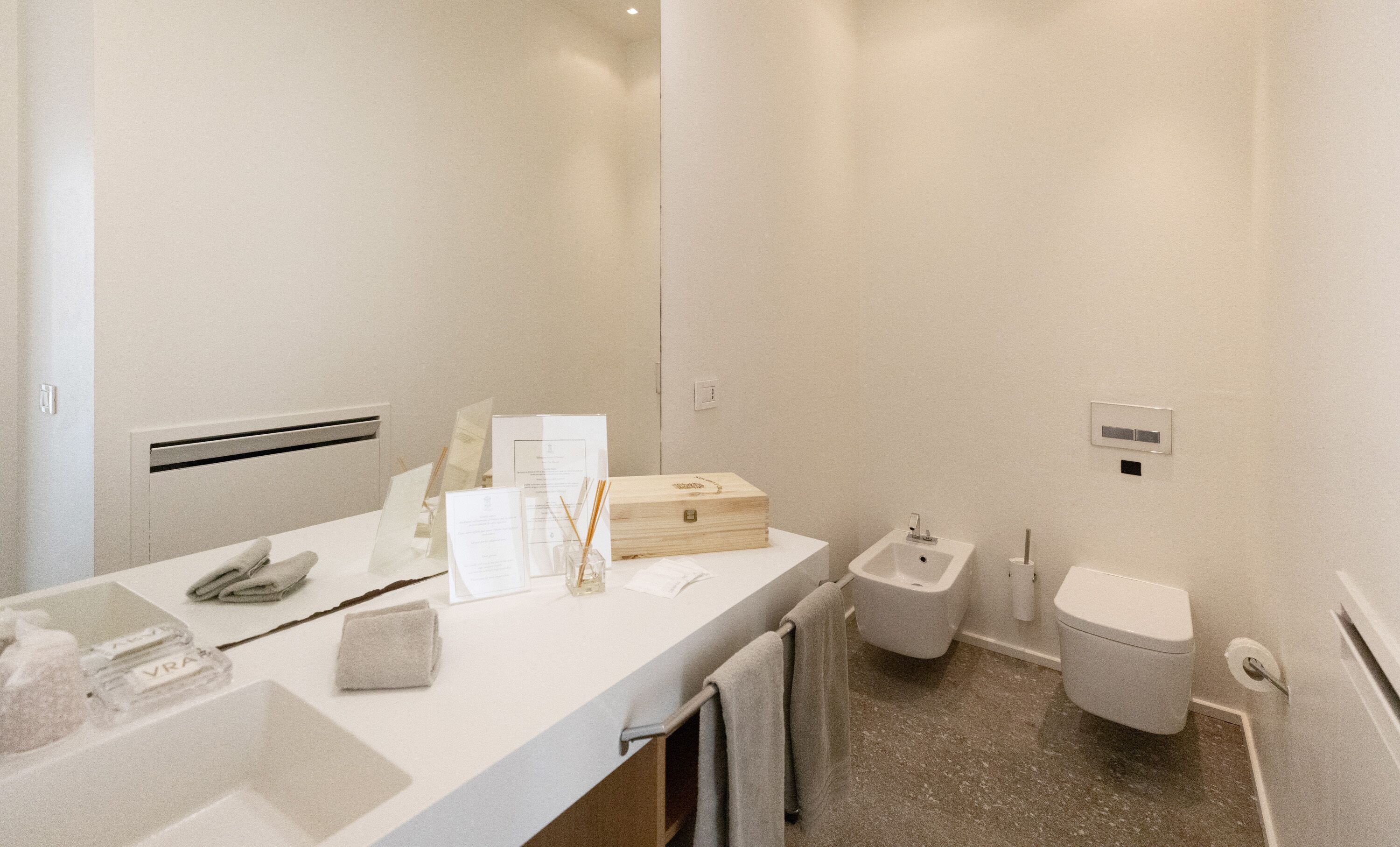 A modern bathroom with a white vanity, a bidet, and a toilet.