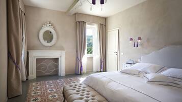 A bedroom with a large bed, a fireplace, a mirror, and a view of the outdoors.