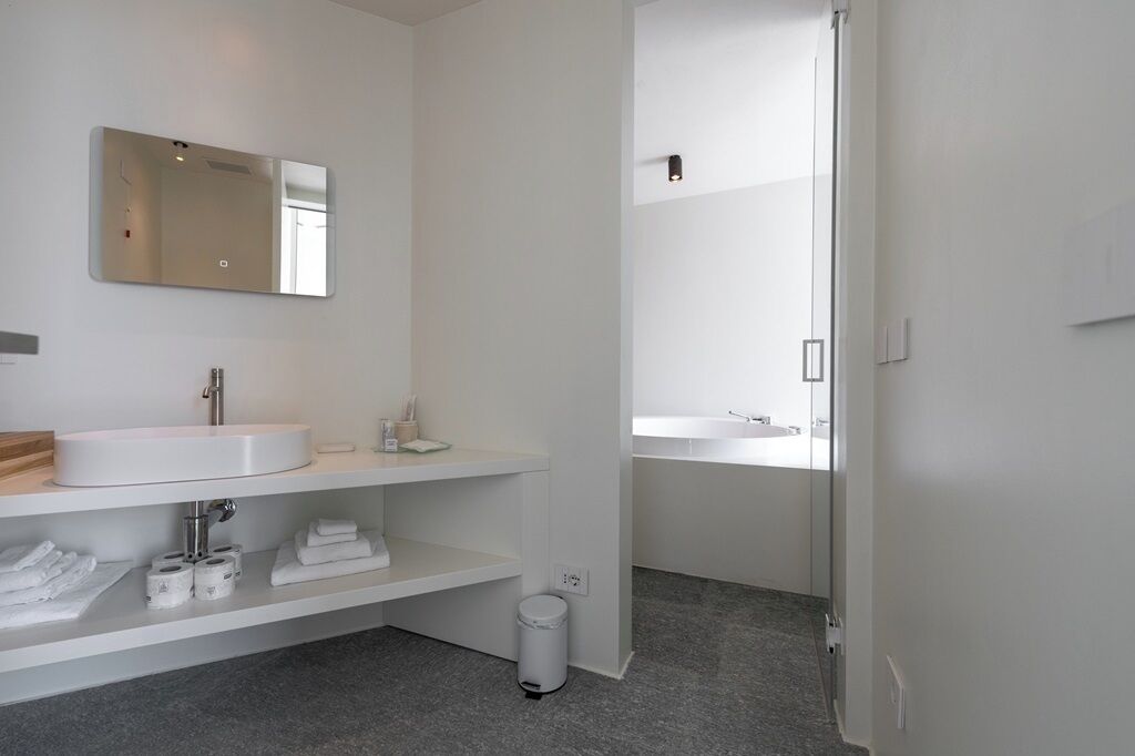 A modern bathroom with a large mirror, a white sink, and a shower area.