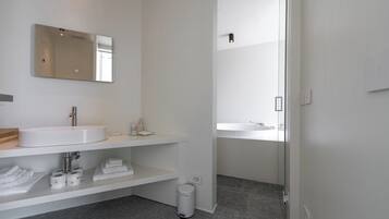 A modern bathroom with a large mirror, a white sink, and a shower area.