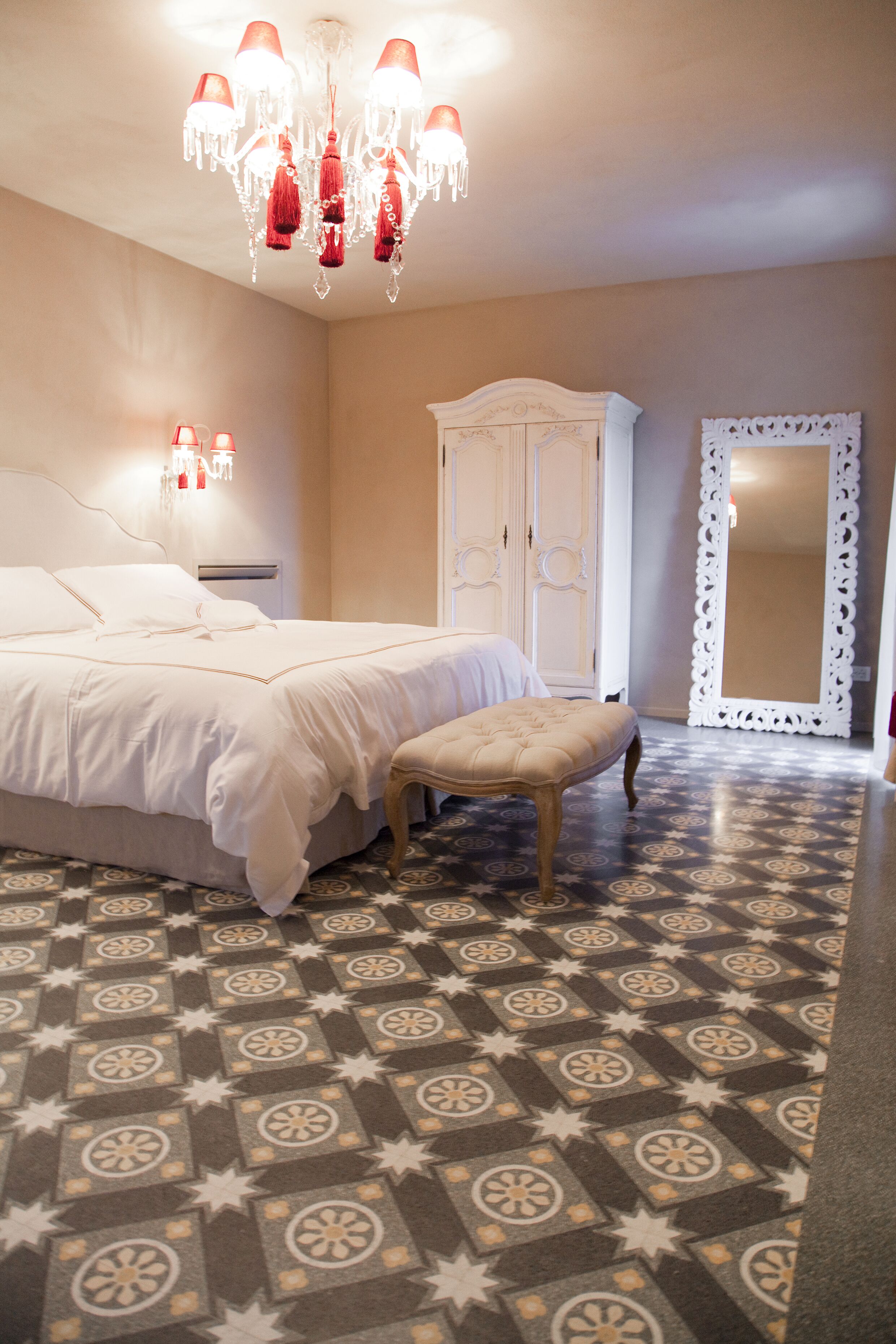 Un dormitorio con cama, banca, armario y espejo.
