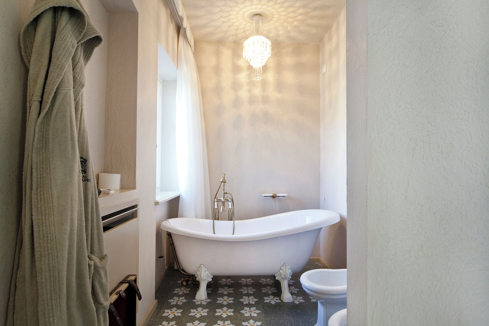 Un bagno con una vasca freestanding, un water e un accappatoio appeso al muro.