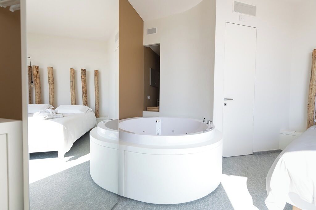 Habitación de hotel moderna con un jacuzzi circular, una cama y una puerta.