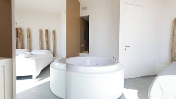 Habitación de hotel moderna con un jacuzzi circular, una cama y una puerta.