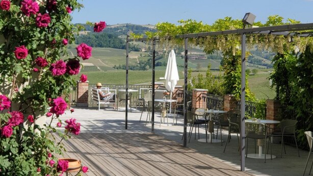 A wooden deck with outdoor seating and a pergola covered with climbing plants. - Palas Cerequio BaroloCruResort (Barolo)