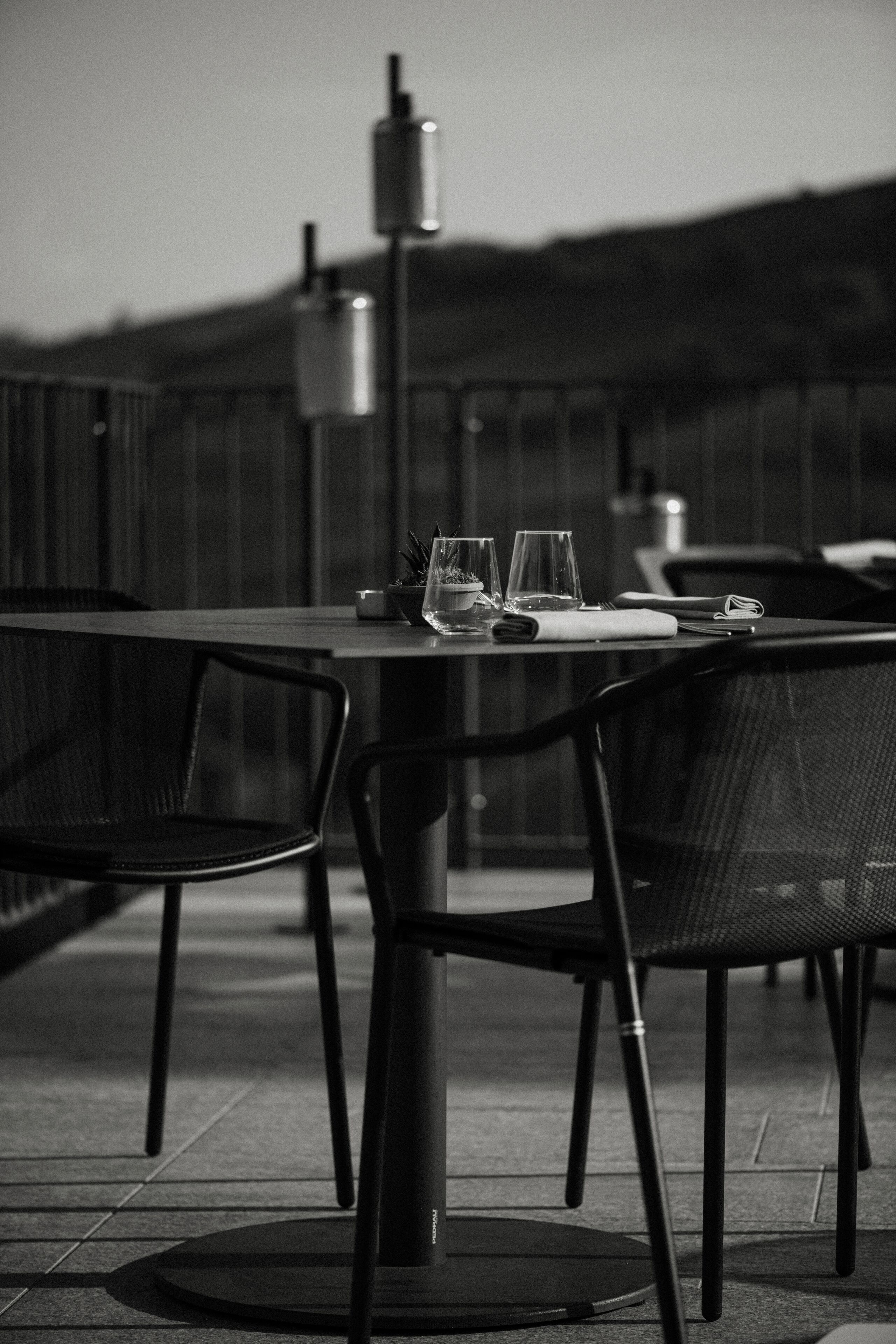 Une table installée à l’extérieur, avec des chaises, une plante en pot et une bouteille.