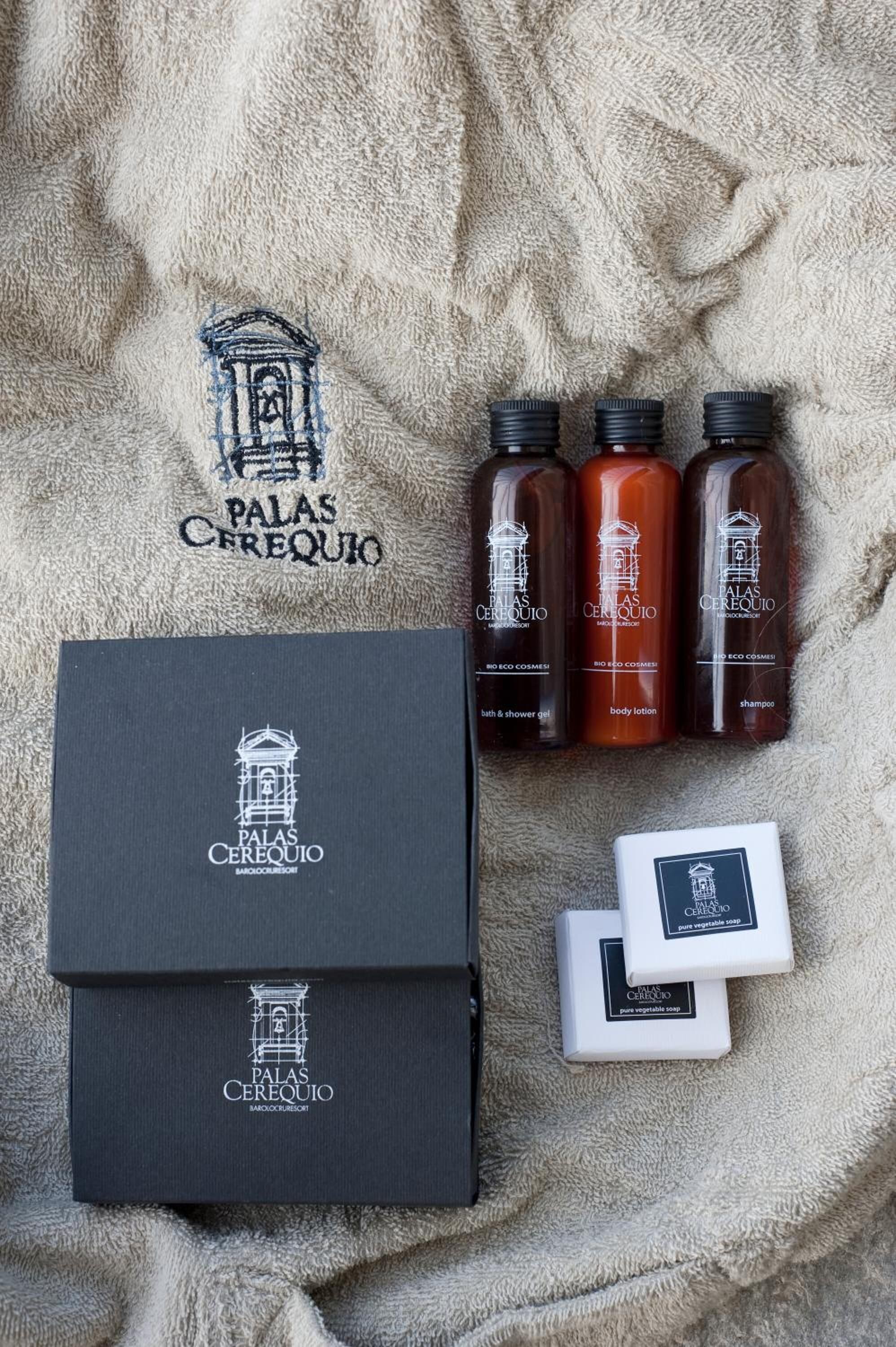 A set of toiletries including a black box, three bottles of body lotion, and two bars of soap, all branded with 'Palas Cerequio'.