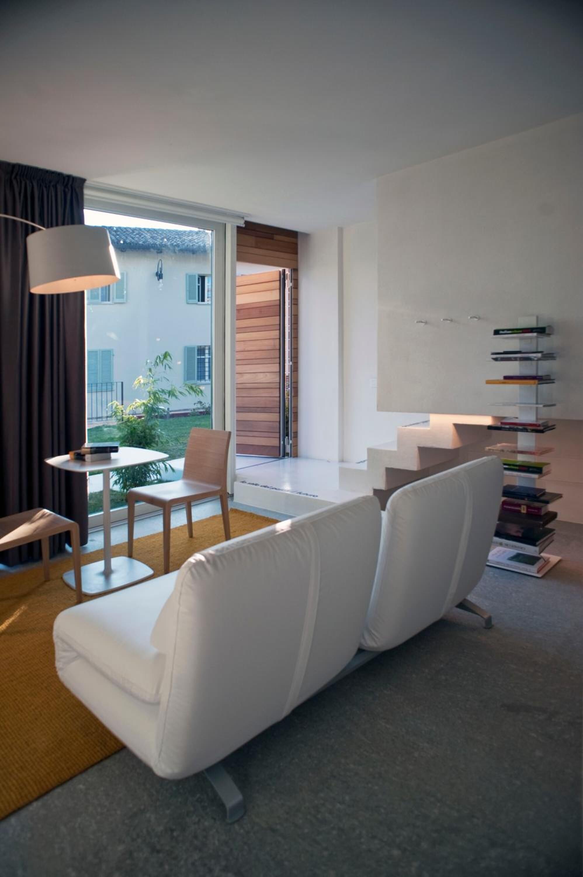 A modern living room with a white sofa, a small table, and a bookshelf.
