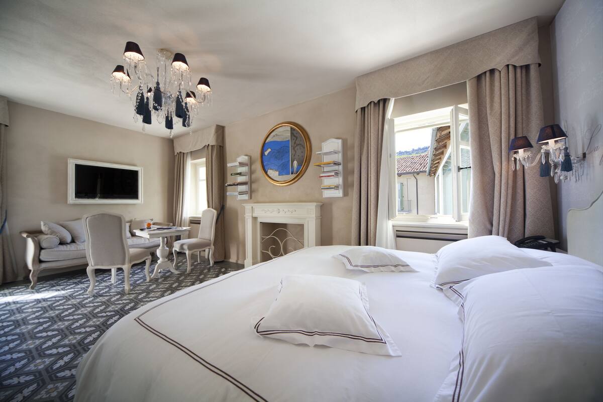 Una habitación de hotel con una cama grande, un sofá, un escritorio y una chimenea.