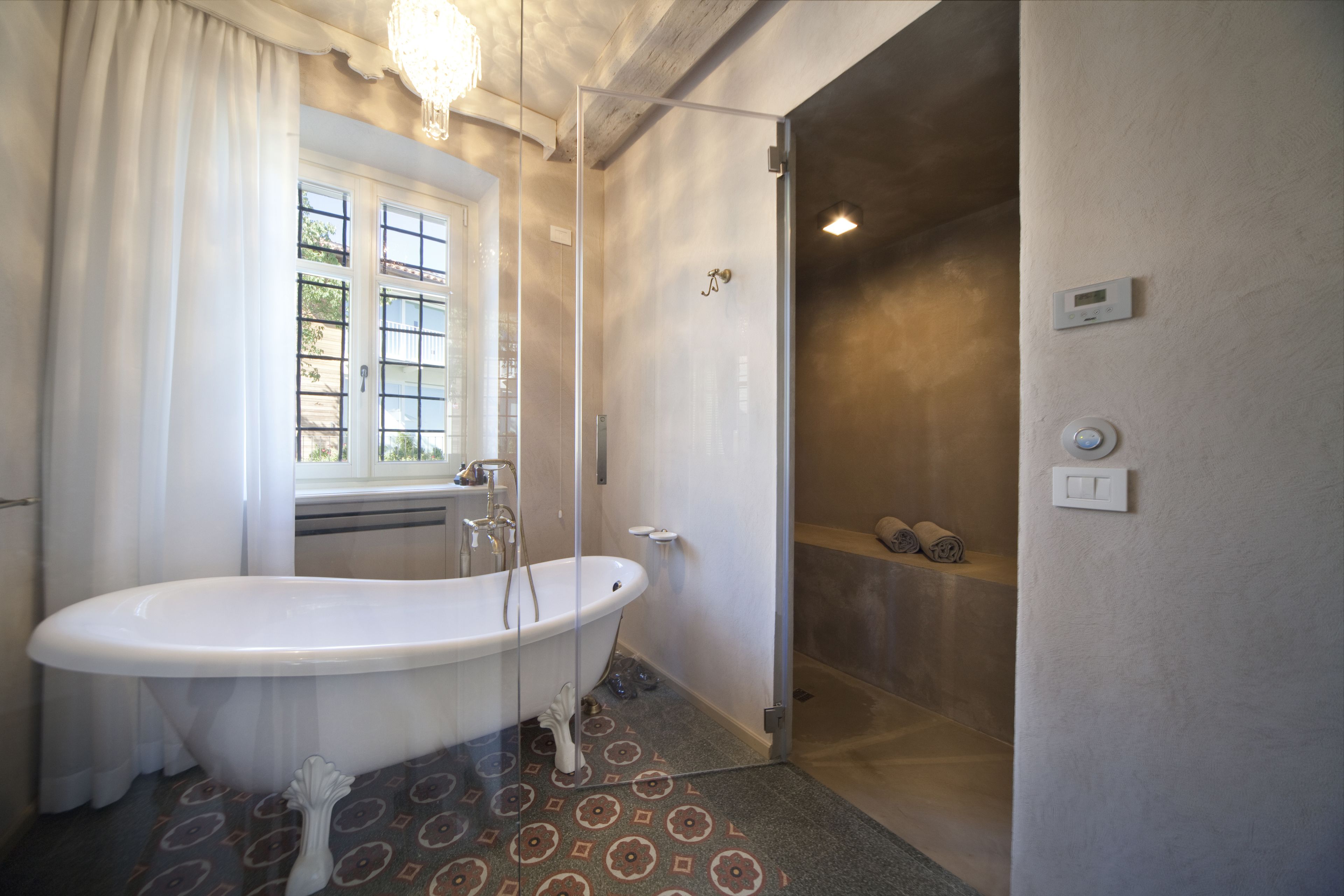 Ein Badezimmer mit einer freistehenden Badewanne, einer Dusche und einem Fenster mit Vorhängen.