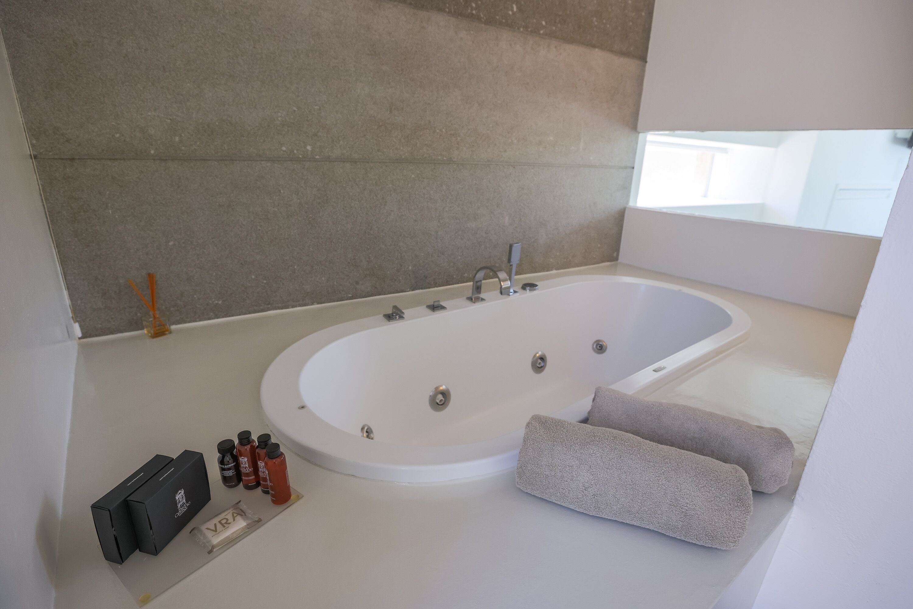 A modern bathroom with a large freestanding bathtub, a small table with toiletries, and a towel.