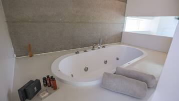 A modern bathroom with a large freestanding bathtub, a small table with toiletries, and a towel.