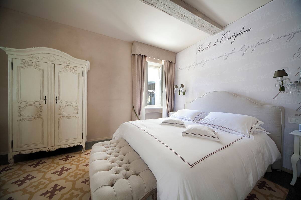 Un dormitorio con una cama grande, un armario blanco y una alfombra estampada.