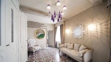 A room with a patterned floor, a beige sofa, a white armchair, and a chandelier.