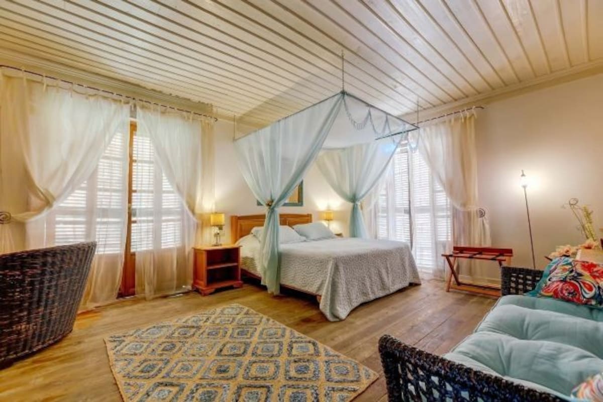 A bedroom with a bed, bedside tables, a chair, a sofa, and a patterned rug.