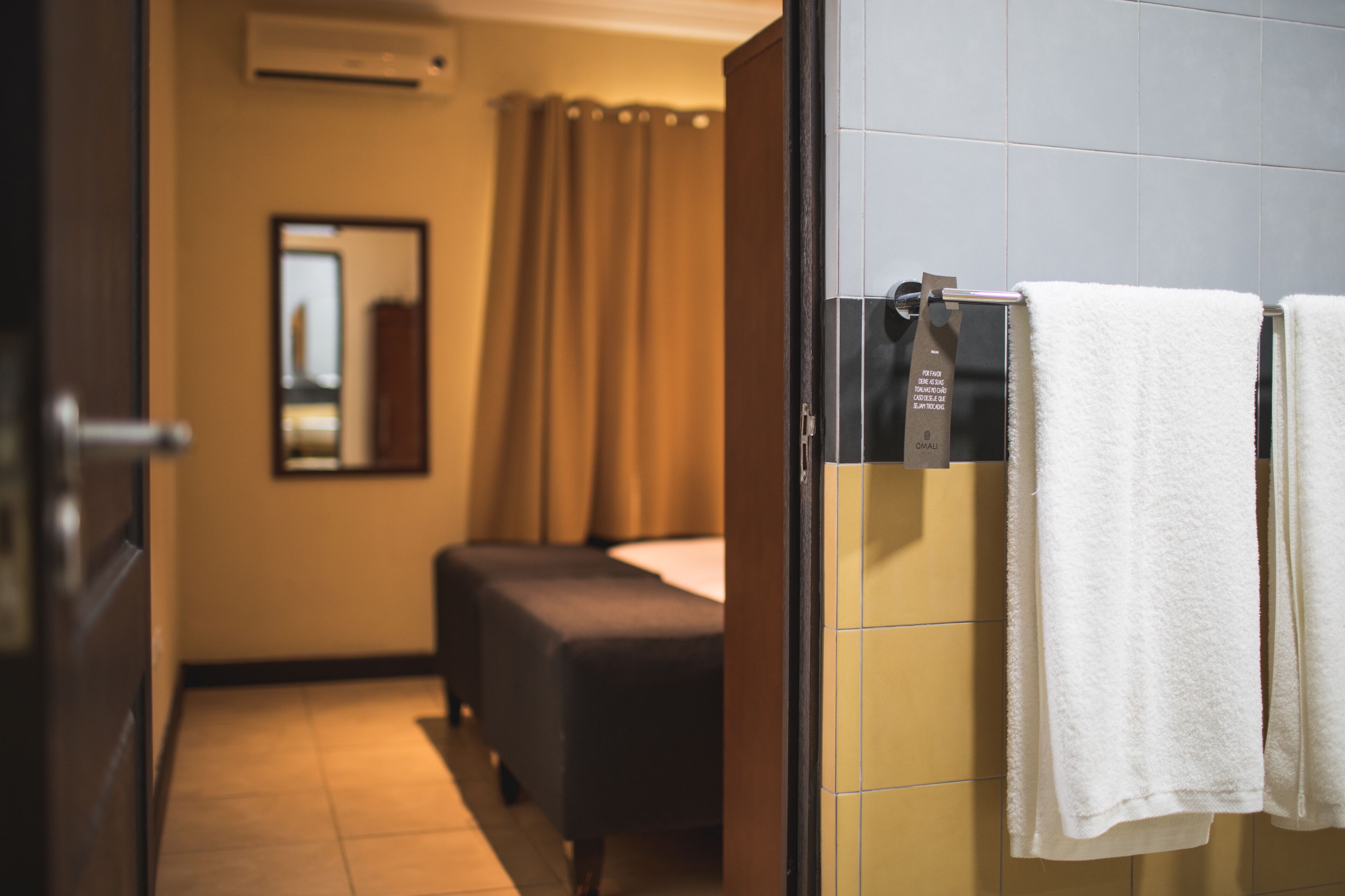 A hotel room with a bed, a small seating area, and a bathroom with towels.