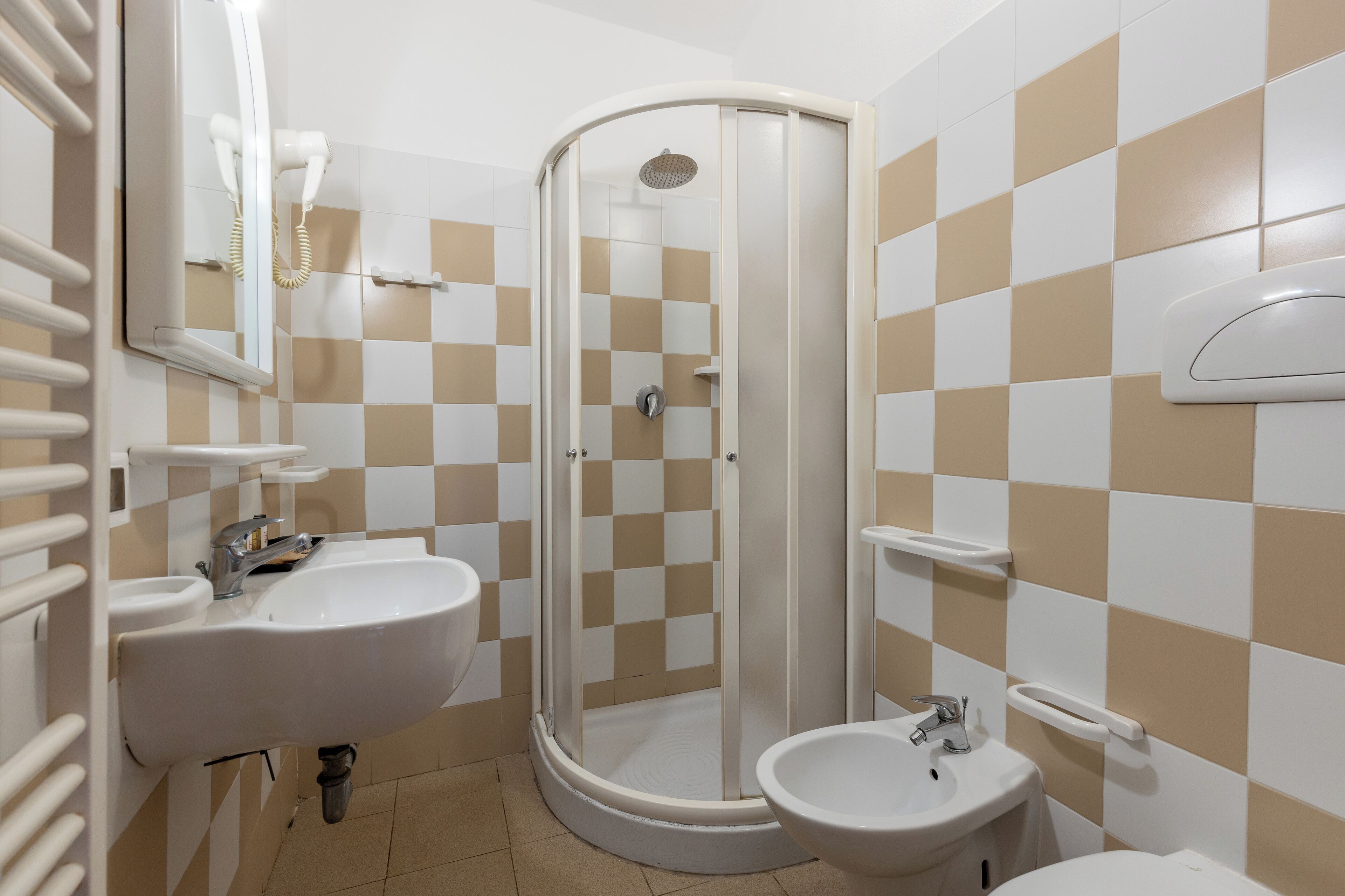 A bathroom with a shower, sink, and bidet.