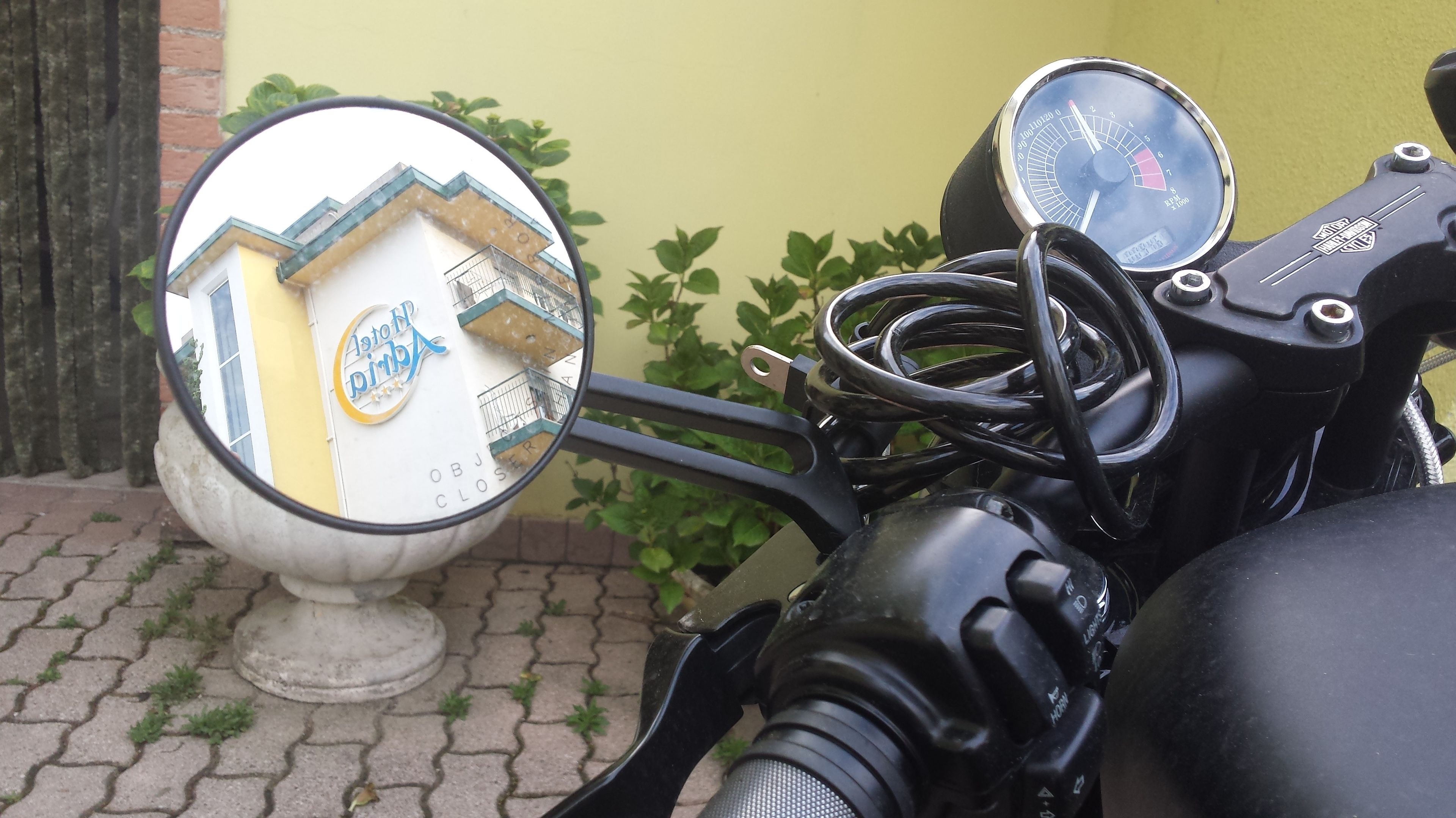 Una motocicleta con un espejo lateral que refleja un edificio con un letrero que dice "Astoria".
