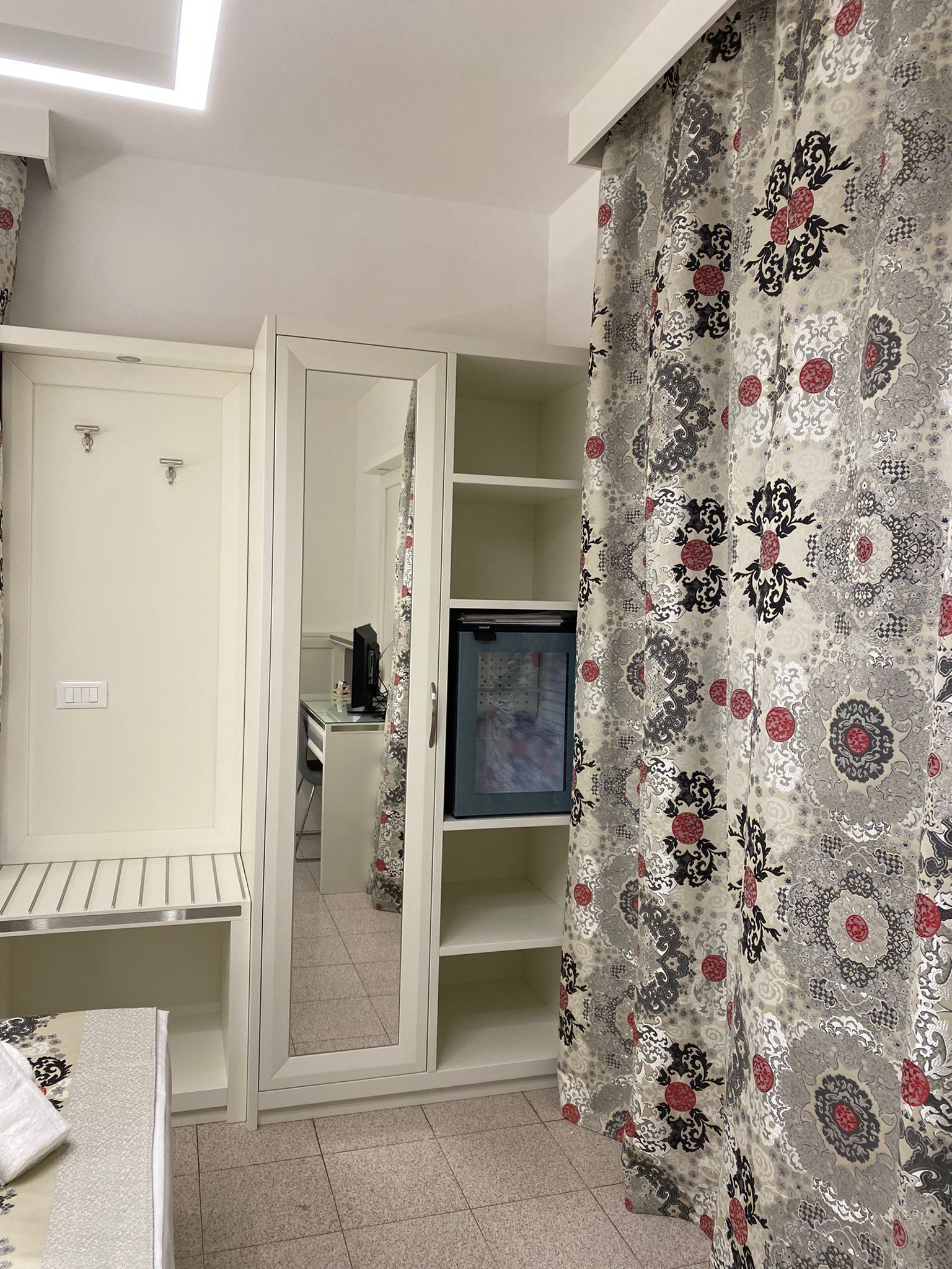 A room with a wardrobe, a desk, and a television.
