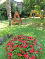 A garden with a swing set, a yellow slide, and red flowers.