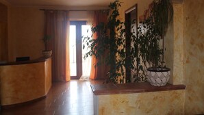 A reception area with a curved reception desk, a potted plant, and a doorway leading to another room. - B&B Giorgia Airport (Fiumicino)