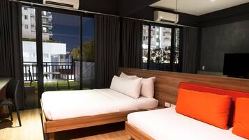 A modern hotel room with a large bed, a smaller bed, a desk, and a TV.