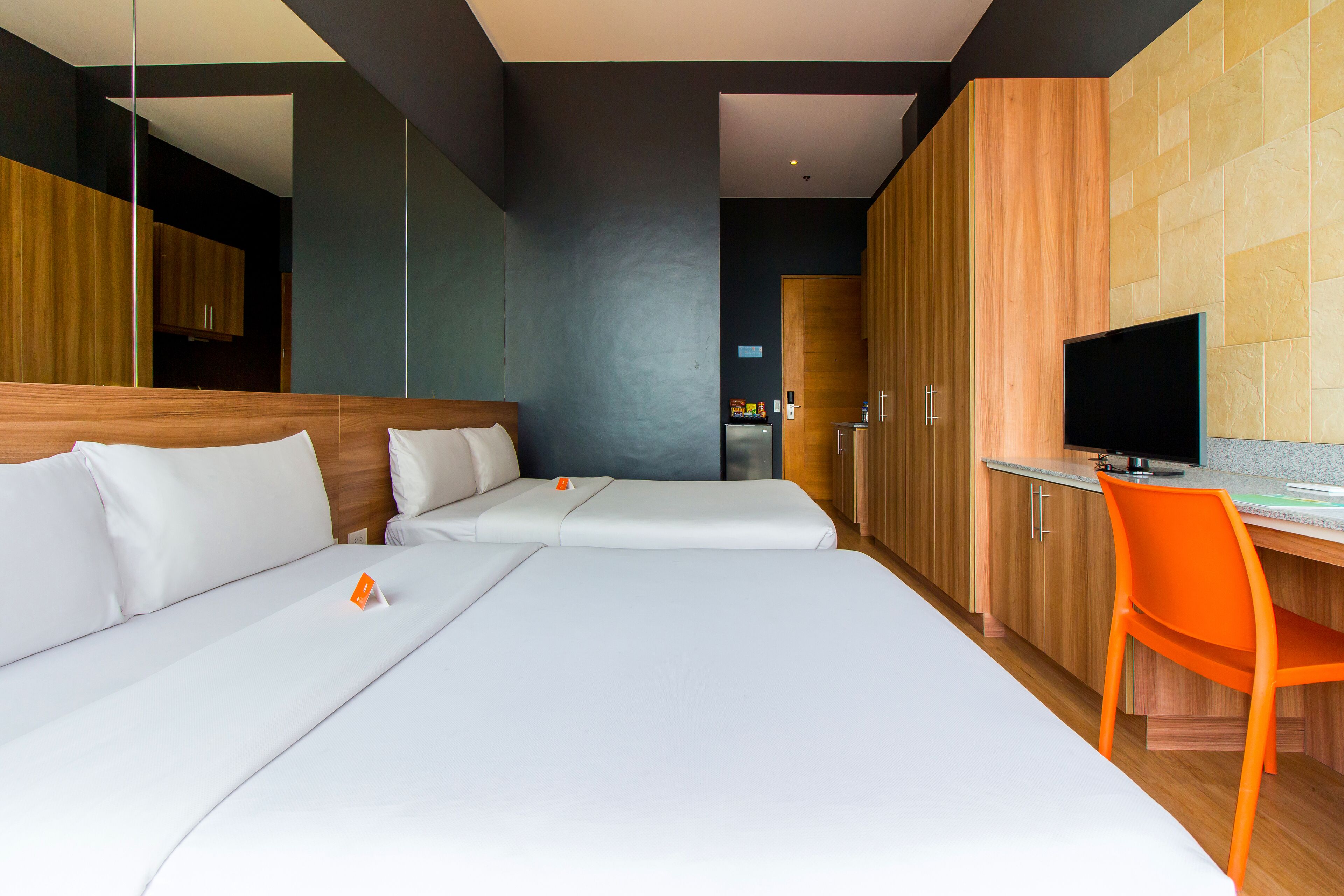 A modern hotel room with a large bed, a desk, and a TV.