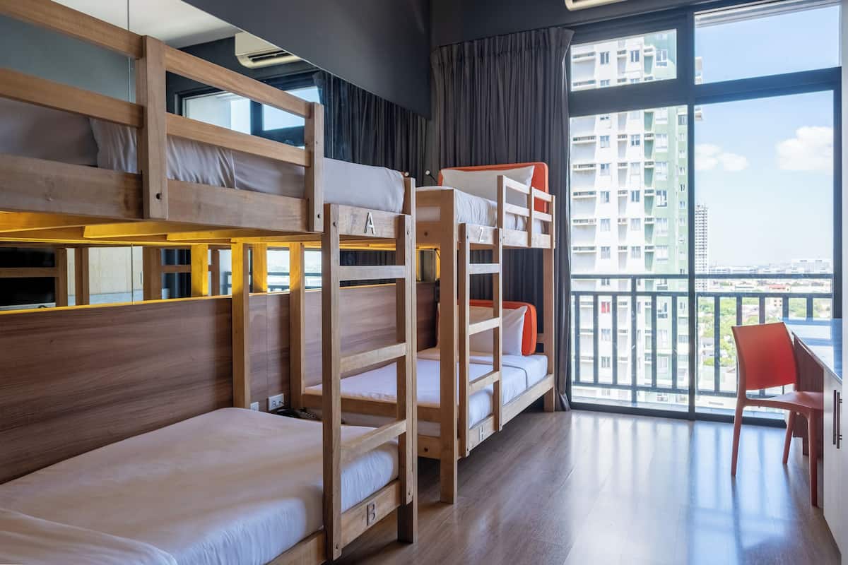 A modern hotel room with bunk beds, a balcony with a city view, and a red chair.