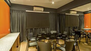 A conference room with a glass table, chairs, and a long table with a counter.