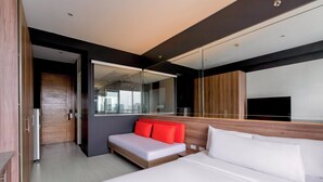 A modern hotel room with a large bed, a smaller sofa, a mirror, and a wardrobe. - Azumi Boutique Hotel (Muntinlupa)