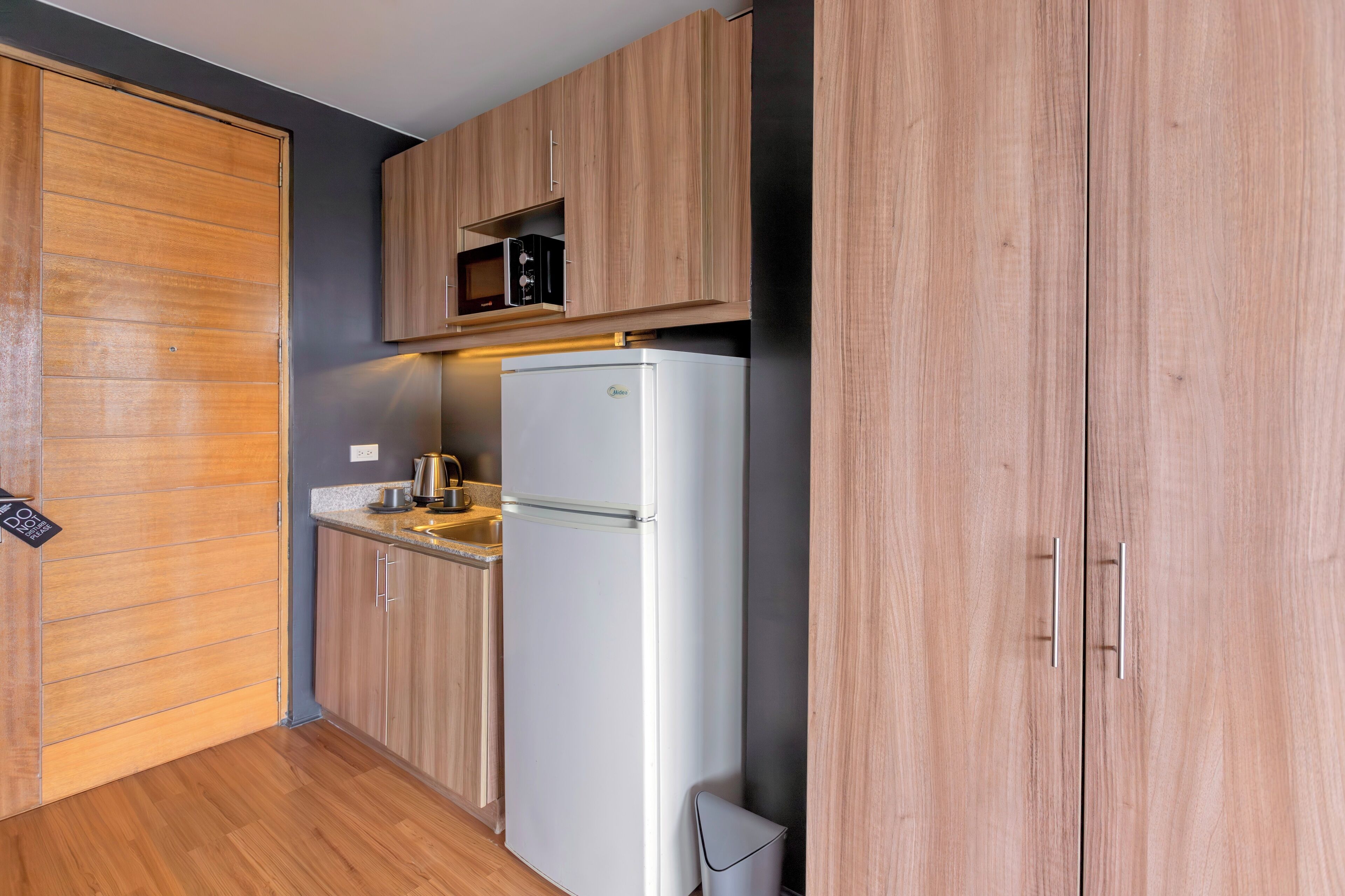 A compact kitchen with wooden cabinets, a built-in microwave, and a white refrigerator.